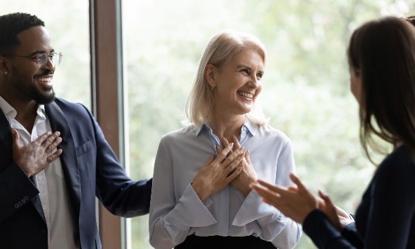 Woman and man smiling at another colleague demonstrating a strong organizational culture.